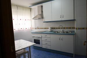 a kitchen with white cabinets and a sink and a table at Hospedium DLJ Arjona Centro I in Arjona