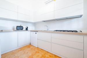 a white kitchen with white cabinets and a microwave at Villa Vimade con Piscina Privata in Marina di Mancaversa