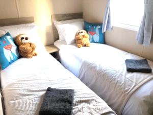 two teddy bears sitting on two beds in a bedroom at Caravan in morecombe in Morecambe