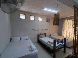 a room with two beds and a chair in it at Hostal Xiinbal Valladolid in Valladolid