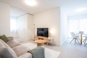 a living room with a couch and a tv and a table at STAYY Flagship Limmattal in Schlieren