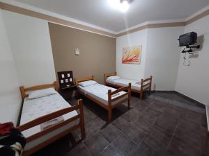 a room with two beds and a tv on the wall at HOTEL TABARANA in Ubarana
