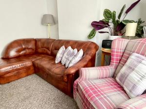 a brown leather couch and a chair in a living room at Purple Cloud Cosy 4 bed Cottage with Garden Parking Pet-Friendly in Portsmouth +28 photos