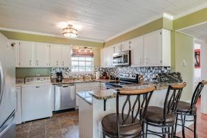 a kitchen with white cabinets and a island with bar stools at East End Beach Side Bungalow in Dauphin Island
