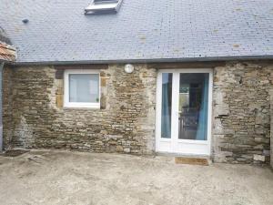 a brick house with a white door and windows at Le gîte du havre in Portbail