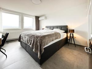 een slaapkamer met een bed, een bureau en 2 ramen bij SI-View Doppelzimmer mit Stadtblick Zimmer 18 in Siegen