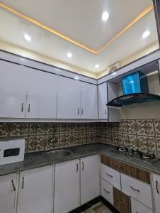 a kitchen with white cabinets and a stove at Central Residence in Gujrānwāla