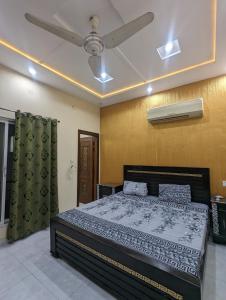 a bedroom with a bed and a ceiling fan at Central Residence in Gujrānwāla