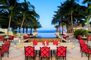 un patio con mesa, sillas y piscina en Acqualina Resort and Residences en Miami Beach