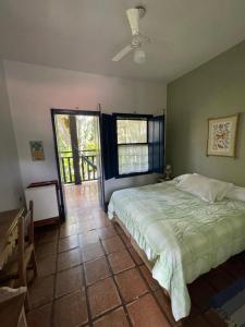 een slaapkamer met een bed en een groot raam bij Hotel Solar das Águas Cantantes in Ubatuba