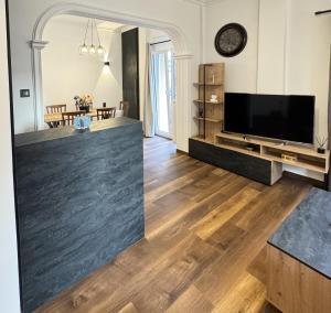 sala de estar con TV de pantalla plana y suelo de madera. en Navaro Apartments, en Patra