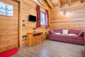 Cabaña de madera con sala de estar con sofá y TV. en Trilocale Chalet Camping Faè 6, en Madonna di Campiglio