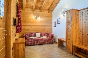 sala de estar con sofá y paredes de madera en Trilocale Chalet Camping Faè 6, en Madonna di Campiglio