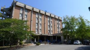 duży ceglany budynek z samochodami zaparkowanymi przed nim w obiekcie Hotel Grassetti w mieście Corridonia