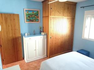 1 dormitorio con cama blanca y armarios de madera en Casa La Calilla, en San José