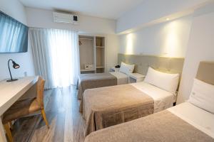 Habitación de hotel con 2 camas y escritorio en Sennac Hotel en Mar del Plata