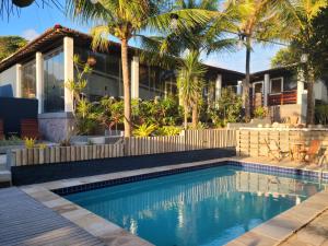 uma piscina em frente a uma casa com palmeiras em Arandu Sagi Inn em Baía Formosa