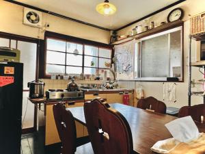a kitchen with a wooden table and a dining room at Guesthouse Azumaya in Matsumoto