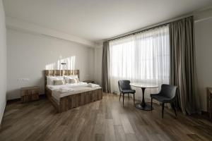 una camera da letto con un letto, un tavolo e delle sedie di Eclipse Winery Boutique Hotel a Kvareli