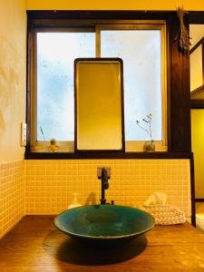 a bathroom with a green sink and a window at Guesthouse Azumaya in Matsumoto