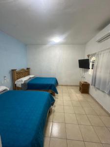a room with two beds and a flat screen tv at Casa Gaviota Casa Con Alberca y Palapa in Tequesquitengo