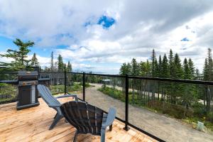 a patio with a grill and two chairs on a deck at Les Chalets du Massif de Charlevoix in Petite-Rivière-Saint-François