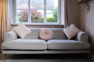 a couch in a living room with two windows at Lambert Cottage - In the Heart of Stamford in Stamford