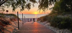 a group of people walking on the beach at sunset at Seaview Apartment & rooftop terrace 77b in Rowy +16 photos