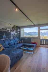 a living room with a blue couch and a large window at Wolfgangsee Appartements in Strobl