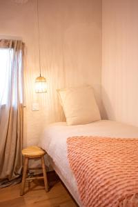 a bedroom with a bed and a stool next to a window at La Maison des Lamanon in Salon-de-Provence
