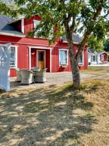 a red building with a table and chairs next to a tree at Strandbergs Stugor in Mariehamn +37 photos
