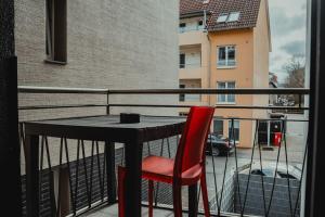 una silla roja sentada en una mesa en un balcón en 3-Zimmer-Oase-Cityapartment Bielefeld Mitte 301, en Bielefeld