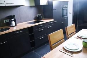 una cocina con armarios negros y una mesa con sillas en 3-Zimmer-Oase-Cityapartment Bielefeld Mitte 301, en Bielefeld