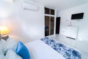 1 dormitorio blanco con 1 cama y TV en Captivating 2-1 with Ocean Views, en Las Flores