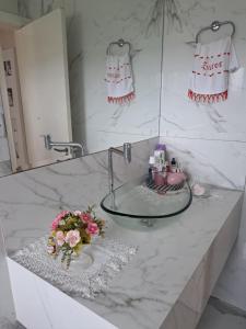 uma casa de banho com lavatório e flores num balcão em Excelente Quarto prox centro Criciuma em Criciúma