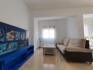 sala de estar con sofá y centro de entretenimiento azul en Piso cerca playa Almeria en Almería