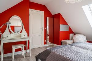 sypialnia z czerwonymi ścianami, łóżkiem i lustrem w obiekcie Pokoje Goscinne Columbus w Karwii