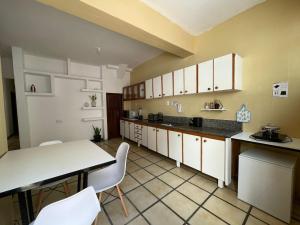 a kitchen with white cabinets and a table and chairs at Pousada aconchegante in Jequié