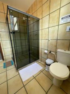 uma casa de banho com um WC e uma cabina de duche em vidro. em Pousada aconchegante em Jequié