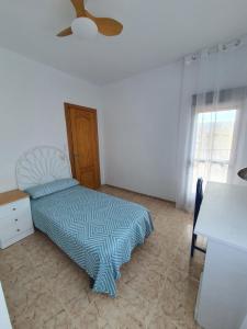 a bedroom with a bed and a table and a window at Piso cerca playa Almeria in Almería