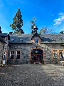 un edificio de piedra con una torre de reloj encima en Fairburn Activity Centre, en Contin