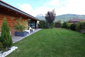 une arrière-cour avec une pelouse et une maison dans l'établissement Chalet indépendant au calme à 10 minutes d'Annecy, à Villaz