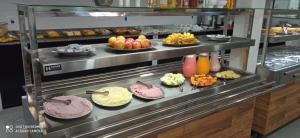 a buffet line with plates of food in a kitchen at Hotel Jardim Paraiba in Aparecida