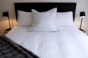 a bed with white sheets and pillows and two lamps at The Town Apartments in Melbourne