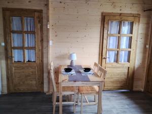 Sasinowe Domki Nad Jeziorem في ماوديته: طاولة خشبية عليها كراسي ومصباح