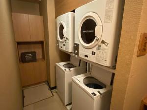 a laundry room with two washing machines and a washer and dryer at Dormy Inn Sendai Station Natural Hot Springs in Sendai