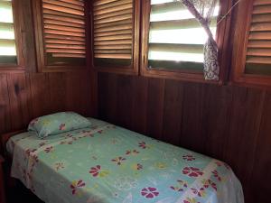 a small bedroom with a bed with a floral bedspread at Chamisal Jungle Hotel in Lima