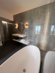 La salle de bains est pourvue d'une baignoire blanche et d'un lavabo. dans l'établissement L'Esplanade, à Domme