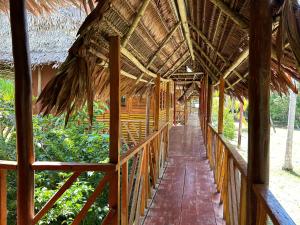a wooden walkway in a straw roofed building at Chamisal Jungle Hotel in Lima