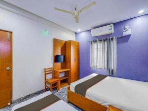 um quarto com paredes roxas e uma cama e uma cadeira em Collection O elegant residency em Chennai